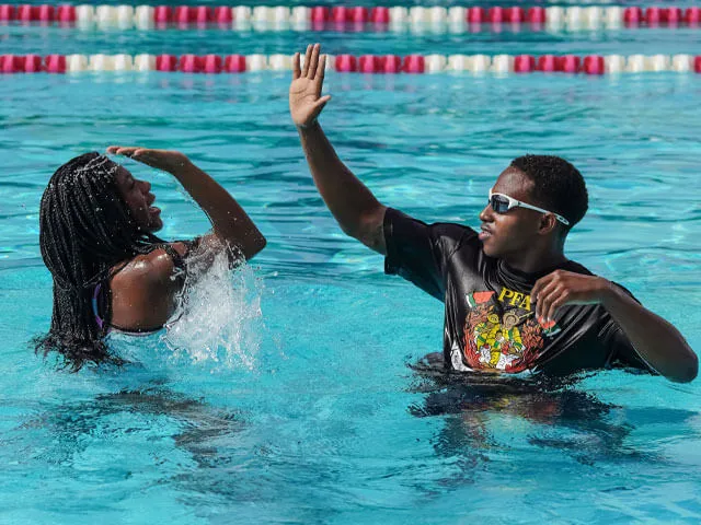 PFA member is giving a high five to a teen learning how to swim.